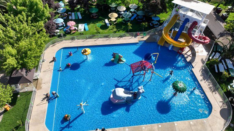 Vista aérea de la piscina Acuafly, con juegos acuáticos en el centro y quitasoles alrededor